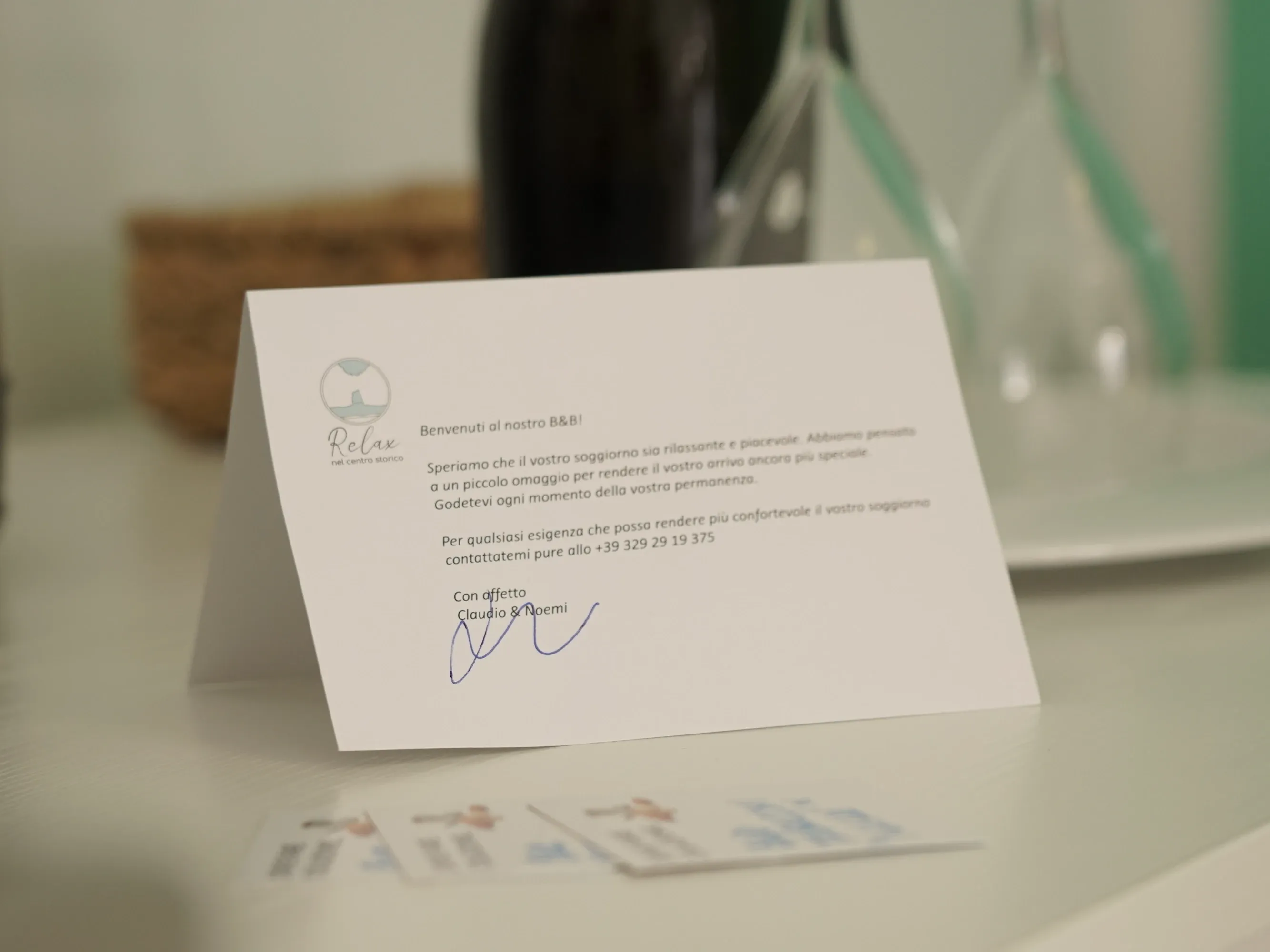 Tarjeta de bienvenida firmada por Claudio y Noemi, con tarjetas de visita delante