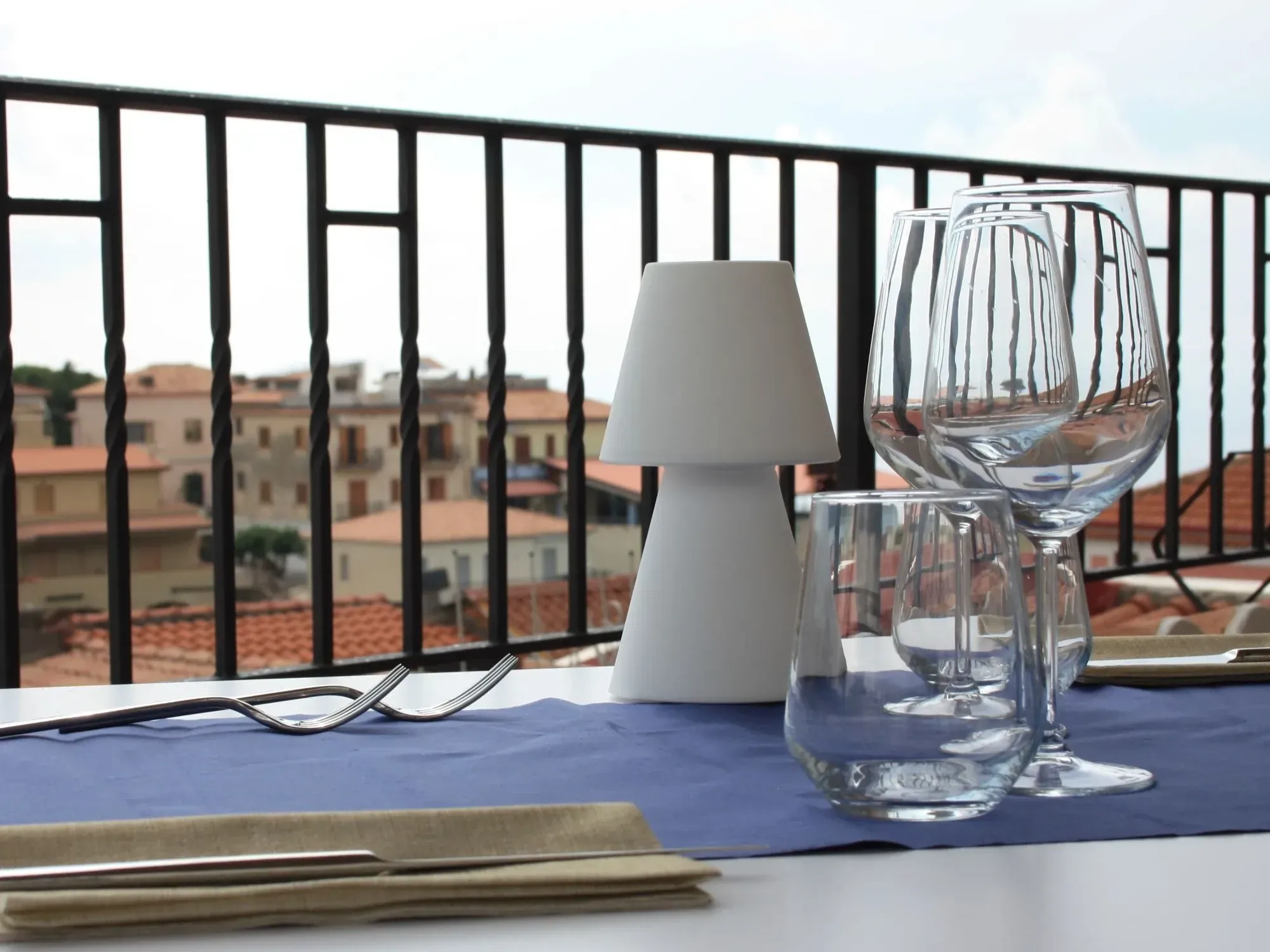 Mesa puesta en un balcón con vistas a los tejados de terracota del pueblo